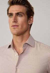 Chemise à carreaux rose clair avec un col structuré, boutonnage sur le devant et des détails de texture subtils. Design décontracté adapté à diverses occasions.
