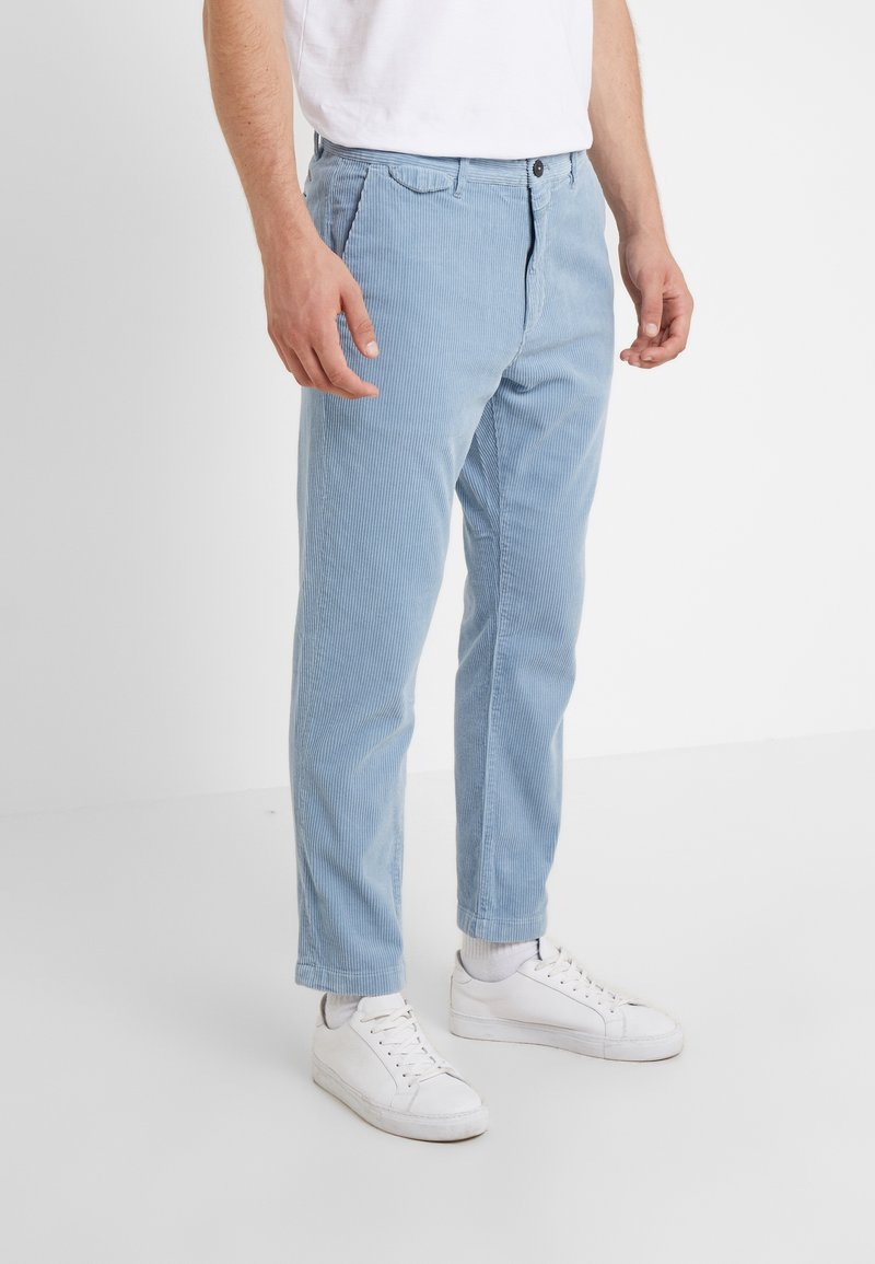 Ljusblå kordflodbyxor med rak passform, med en frontknäppning och sidofickor, ihop med vita sneakers.