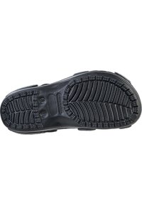 Zwarte schoenzool met diepe looppatronen en uitsparingen voor grip. Heeft een ronde vorm, een gladde afwerking en gemodelleerde merktekens.