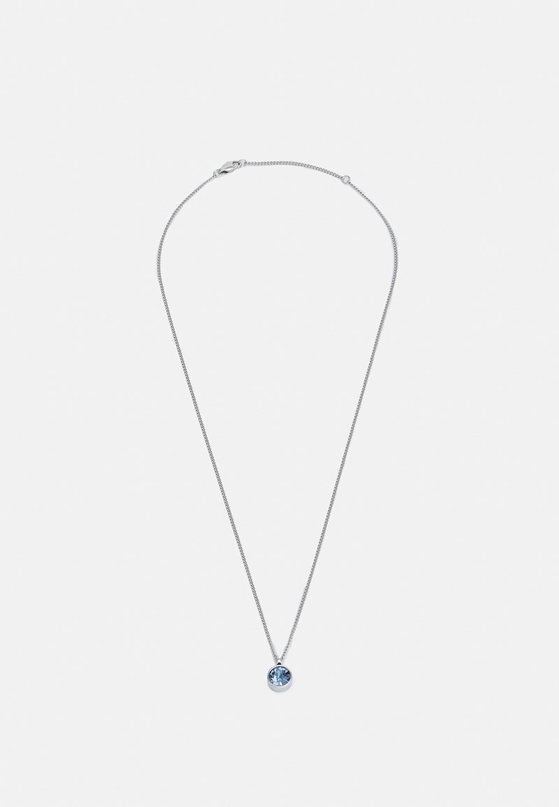 Collier chaîne en argent avec un pendentif unique en forme de pierre précieuse ronde bleue centré sur un fond clair uni.