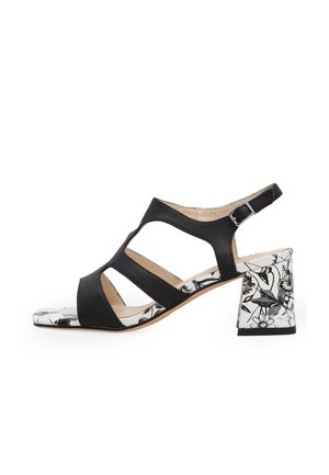 Czarna sandałka na odkryte palce z wyciętymi paskami, regulowaną klamrą na kostkę oraz kwiatowym wzorem na bloku obcasa i akcentach podeszwy.