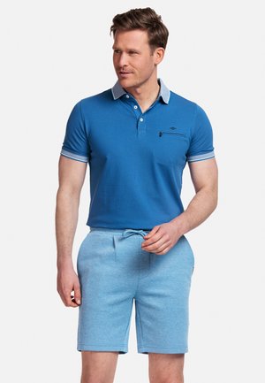 Blauwe polo met een contrasterende grijze kraag, voorzien van drie knopen en een borstzak. Gecombineerd met lichtblauwe shorts met een trekkoord in de taille.