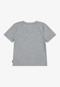 T-shirt gris à manches courtes en tissu doux. Doté d'un col rond et d'une petite étiquette logo rouge sur le côté gauche. Texture lisse.