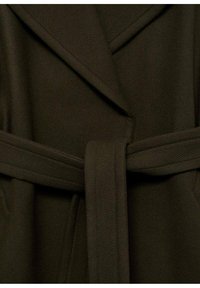 Manteau enveloppant vert foncé en tissu texturé, avec de larges revers et une ceinture assortie nouée à la taille. Design ajusté avec poches latérales.