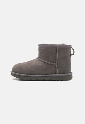 Stivale alla caviglia in suede grigio con punta arrotondata, dettagli cuciti, gambale corto e suola in gomma texturizzata. Fodera morbida visibile nella parte superiore.