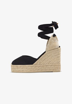 Espadrille compensée en toile noire avec plateforme en jute tissé et liens à nouer autour de la cheville.