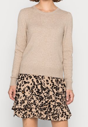 Maglione lavorato a maglia beige con scollo rotondo e maniche lunghe, abbinato a una gonna a balze in stampa leopardata con accenti neri e marroni.