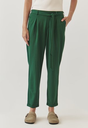 Green, relaxed-fit trousers with a tie waist, side pleats, contrasting stitching, and rolled cuffs. Made from soft, lightweight fabric.