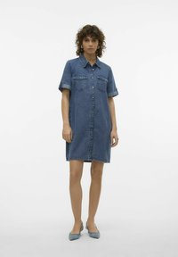 Denim haljina s kratkim rukavima, prednjim kopčanjem na gumbi, dva džepa na prsima i roliranim manžetama u srednje plavoj nijansi. Glatka tekstura.