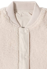 Veste beige clair avec une texture duveteuse, un col côtelé et des boutons-pression. Matière douce et design décontracté, structuré.