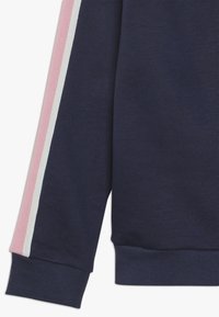 Marineblauwe sweatshirtmouw met ribbeltextuur, voorzien van roze en witte zijkantenstripes nabij de manchetten. Eenvoudig, casual ontwerp.