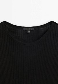 Top in maglia nera a coste con scollatura ampia e texture morbida. Etichetta visibile con informazioni sulla taglia che indicano S, M, L.