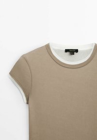 T-shirt beige côtelé à manches courtes avec finition blanche autour du col et des bords des manches, vu de face depuis le haut.