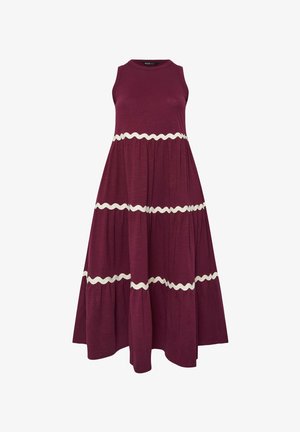 Ærmeløs maxi-kjole i mørkelilla med bred, lagdelt nederdel og tre horisontale hvide bølgede bånd omkring taljen og kanten.
