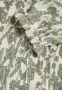 Tissu plissé blanc avec un imprimé floral vert, accents métalliques dorés et détails à volants aux poignets.