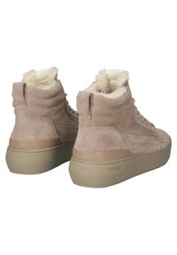 Baskets montantes en daim beige avec des semelles en caoutchouc beige épaisses et une doublure blanche duveteuse, vues de dos et légèrement en angle.