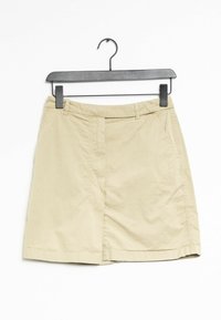 Jupe en coton beige au design droit, dotée d'une fente frontale, de poches latérales et d'une texture lisse. Accrochée à un cintre noir.