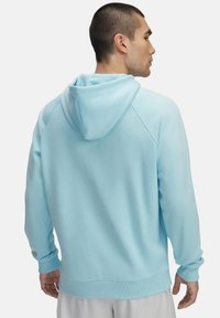 Lichtblauwe, capuchonsweater met een gladde textuur, raglanmouwen en geribbelde boorden. Eenvoudig ontwerp zonder patronen of extra accenten.