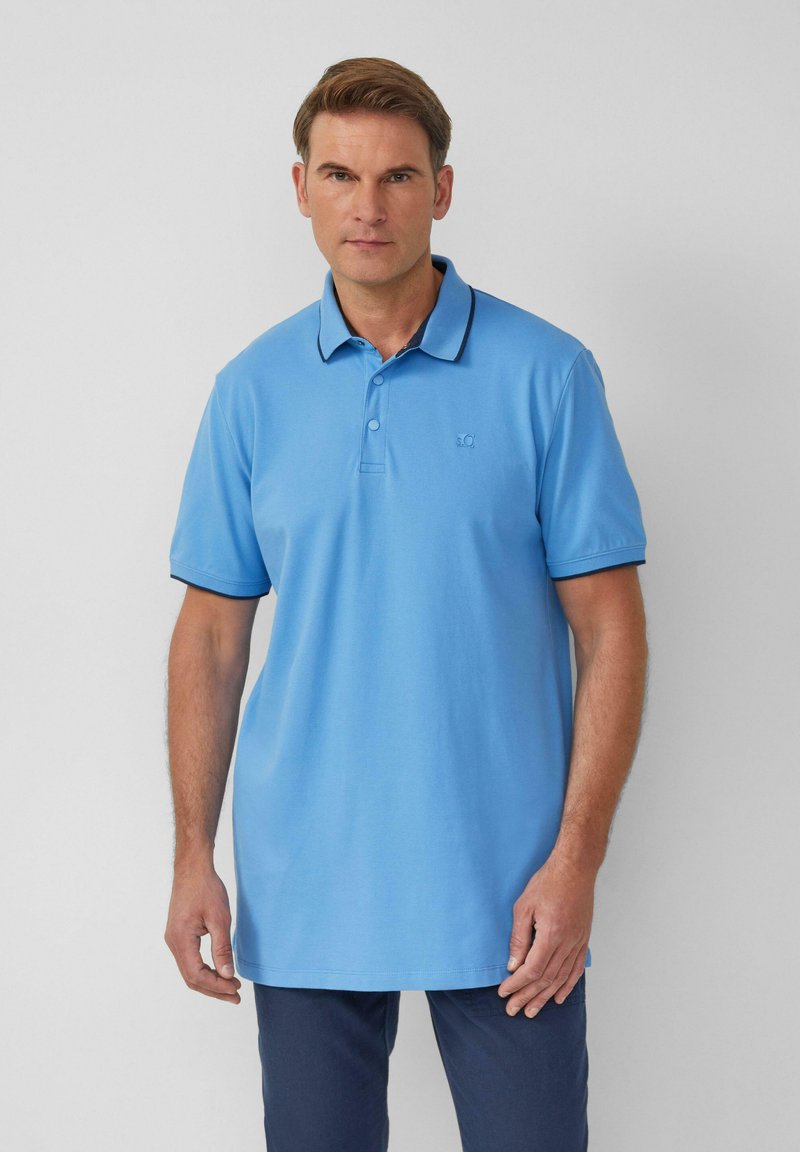 Light blue polo shirt made of cotton, featuring a classic collar, three buttons, and a contrasting dark trim along the collar and sleeves.