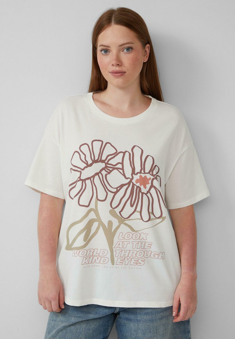 Crème oversized t-shirt met kleurrijk bloemig graphic design in bruin en perziktonen, met de tekst "Kijk naar de wereld door vriendelijke ogen."