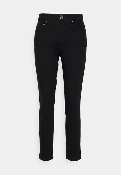 Jeans tapered negros de mezclilla, con cierre de botón, bolsillos delanteros y traseros, y acentos en dorado.