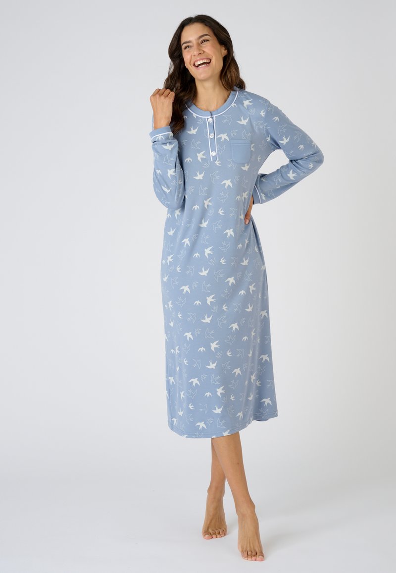 Camicia da notte a maniche lunghe in tessuto azzurro chiaro con motivo di uccelli bianchi, colletto rotondo e apertura con tre bottoni, dotata di taschino sul petto.