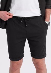 Schwarze Shorts aus texturiertem Material mit einem Kordelzug, zwei Fronttaschen und umgeschlagenen Säumen. Klassisches und vielseitiges Design.