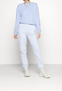 Felpa in cotone azzurro, con maniche lunghe e scollatura rotonda, abbinata a pantaloni della tuta azzurri coordinati con vita elastica.
