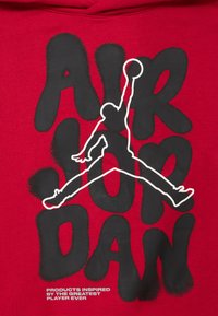 Κόκκινο φούτερ με έντονο μαύρο κείμενο που λέει "AIR JORDAN" και λευκό σιλουέτα ενός πηδού μεταφορά μπάσκετ.