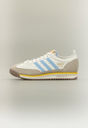 Baskets Adidas SL 72 blanches et beiges avec des rayures bleu clair et un accent jaune sur la semelle, vue latérale sur un fond neutre uni.