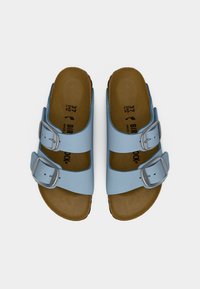 Μπλε σανδάλια τύπου slip-on με δύο ρυθμιζόμενες ασημένιες αγκράφες, καφέ ανατομικό πέλμα και λείο συνθετικό επάνω μέρος.