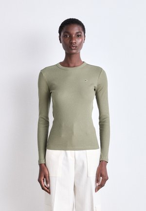 Langärmliges, geripptes Shirt aus olivgrünen Stoff, mit Rundhalsausschnitt und kleinem Logo-Emblem auf der Brust.