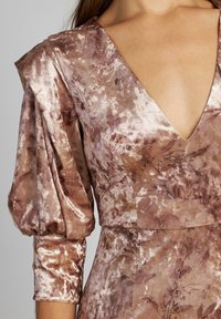 Abito in velluto mauve lucido con motivi floreali, scollatura a V profonda e maniche a tre quarti gonfie con polsini arricciati.