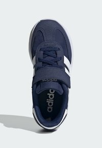 Chaussure de sport bleue avec des rayures blanches, fabriquée en tissu et en matériaux synthétiques, présentant un design à lacets et une sangle ajustable.