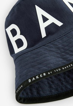 Laivaston malli ämpärihattu, joka on valmistettu teksturoidusta kankaasta. Hatussa on suuret valkoiset kirjaimet, jotka kirjoittavat "BAKER", sekä musta brändinauha hatun alaosassa.