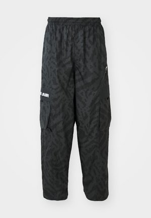 Pantalons cargo noirs avec un motif camouflage texturé, taille élastique, poches latérales et un détail logo blanc sur la jambe.