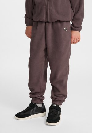 Fleece-Sweatshirt und Hose in dunklem Mauve, mit elastischen Bündchen und Bund. Schwarze Sneakers mit strukturierten Akzenten vervollständigen das Outfit.