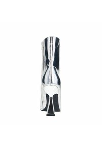 Bottine à talons hauts argentée avec une surface réfléchissante, fermeture à glissière sur le côté et un talon triangulaire qui met en valeur son design moderne.