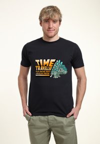 Camiseta de algodón negra con un estampado gráfico de un dinosaurio con espinas azules y el texto que dice "VIAJERO DEL TIEMPO DE OTRO MUNDO PUERTA JURÁSICA."