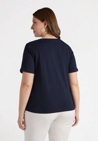 Top de manga corta azul marino, con cuello redondo, tejido suave, ajuste relajado, con una textura lisa y detalles de costura sutiles.