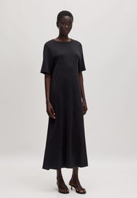 Zwart, mouwloze maxi-jurk van soepel materiaal. Heeft een ronde halslijn en een relaxte pasvorm met een rechte zoom.