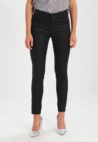Jean en denim noir, ajusté, avec une texture lisse, conçu avec une taille mi-haute et des jambes slim. Présente des coutures minimales et des détails de logo.