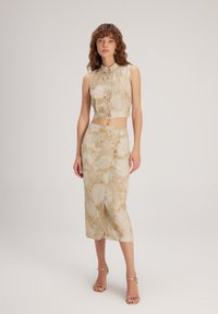 Top corto floral y falda ajustada en tela beige con acentos dorados. Textura suave, detalles de botones y patrones florales intrincados.