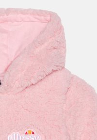 Felpa con cappuccio rosa in pile, con un esterno texturizzato e soffice. Presenta un cappuccio arrotondato e un logo ricamato sul davanti. Fodera interna liscia.