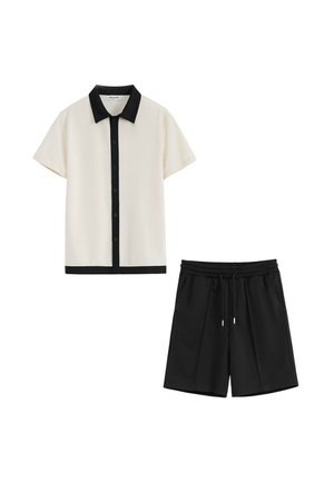 Chemise beige à manches courtes avec col et boutons noirs, associée à un short noir avec taille élastique et cordon de serrage.
