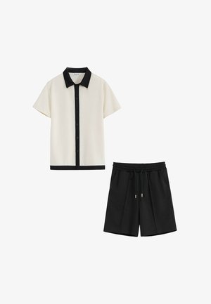 Chemise beige à manches courtes avec col et boutons noirs, associée à un short noir avec taille élastique et cordon de serrage.