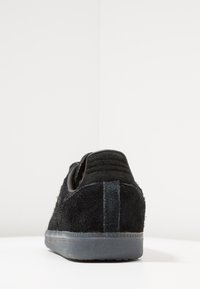 Baskets en su ède noir avec une finition texturée, bout arrondi et semelle en caoutchouc. Comprend une petite languette à l'arrière et un détail de talon contrastant.