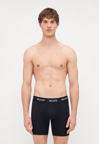 Boxeri negri, din material elastic, cu talie înaltă și cu branding "HOLLISTER". Material neted, design ajustat și acoperire medie a piciorului.