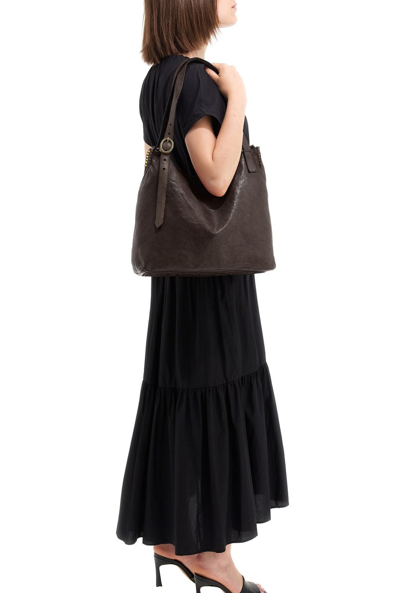 Borsa a tracolla in pelle marrone con finitura lucida, dotata di tracolla regolabile e dettagli in metallo dorato. La silhouette è morbida e sformata.