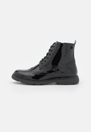 Černé lakované kožené kotníkové boty s šněrováním, brogue detaily, kulatou špičkou a gumovou podrážkou. Mají poutko na zadní straně.